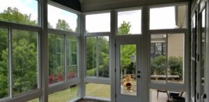 Sunlight streams into a serene sunroom that opens to a lush, peaceful backyard and patio.