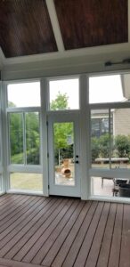 Sunlight fills a serene sunroom, offering a tranquil view of a lush patio with cozy seating.