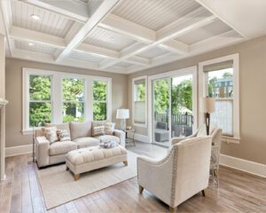 A sunlit living room with soft neutrals offers a serene view of lush North Carolina greenery.