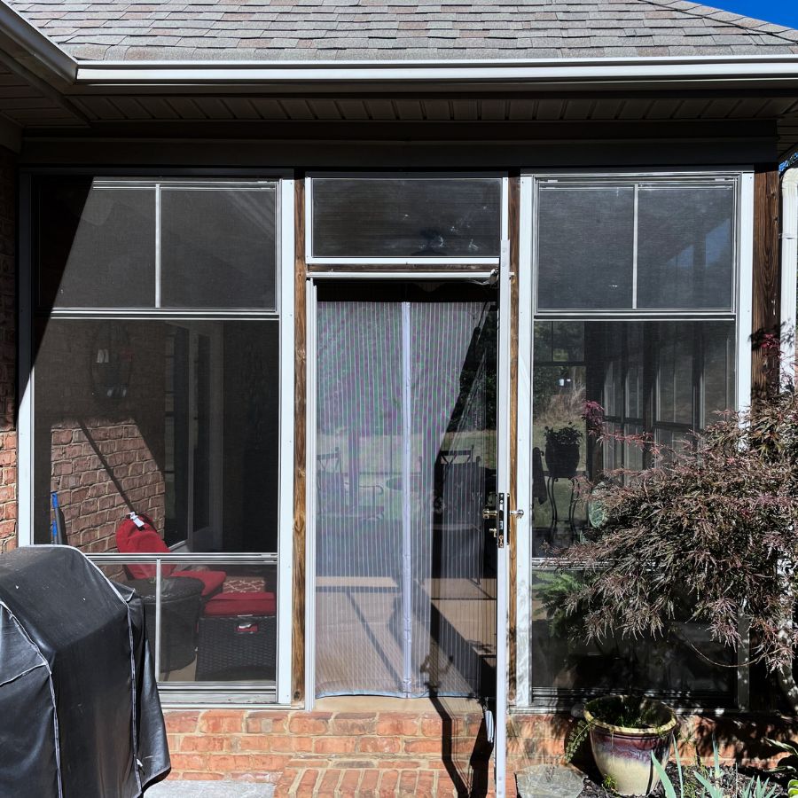 A cozy screened porch features inviting outdoor seating amid brick walls and a peaceful, relaxed vibe.