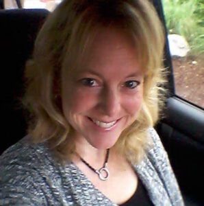 Smiling in her car, a blonde woman fondly recalls her new home window replacement.