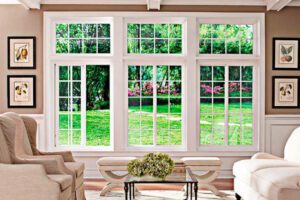 Sunlight pours through large white-trim windows, filling the tranquil living room with garden views.