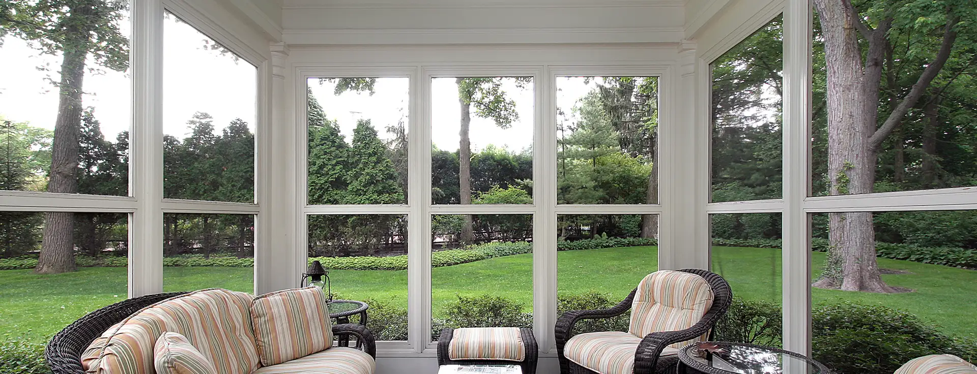 Sunlight fills a cozy sunroom overlooking a lush, tree-lined backyard.
