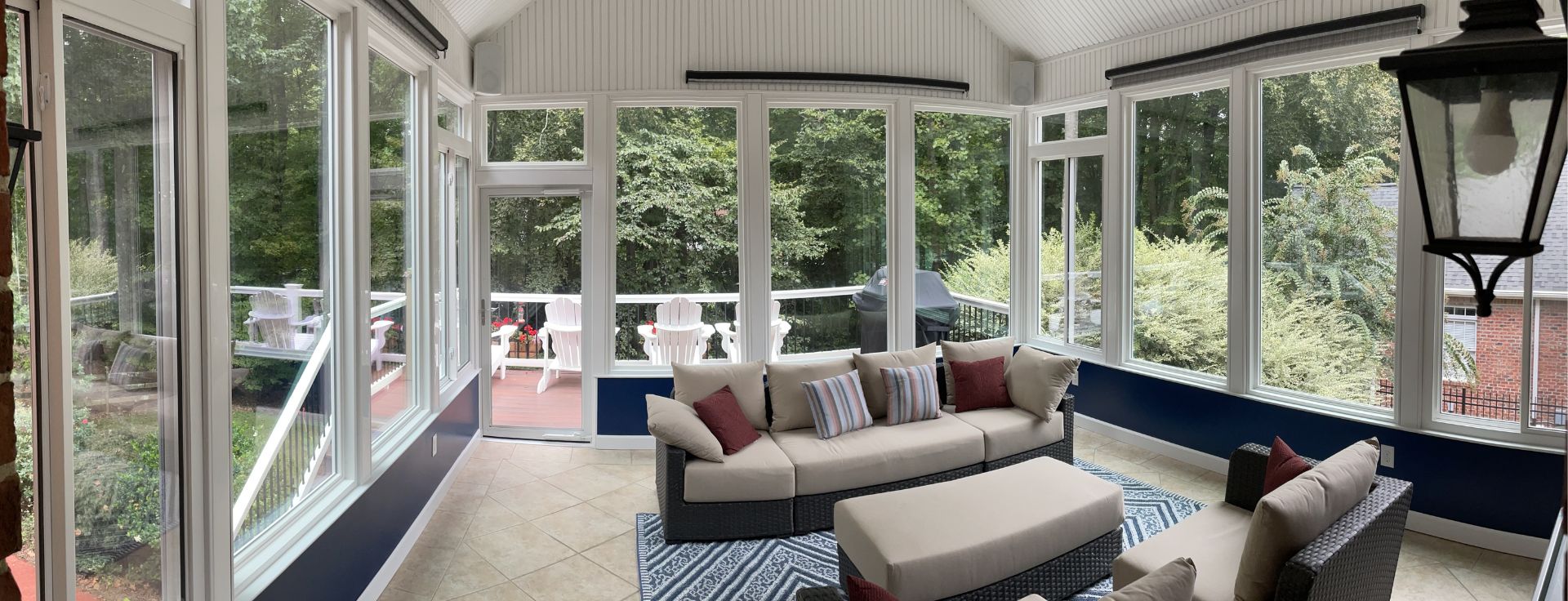 Sunlight streams into a cozy sunroom, blending indoor comfort with peaceful views of lush greenery.