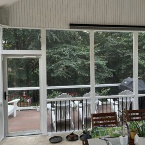 A bright screened porch with white windows creates an inviting, tranquil retreat overlooking a peaceful deck.