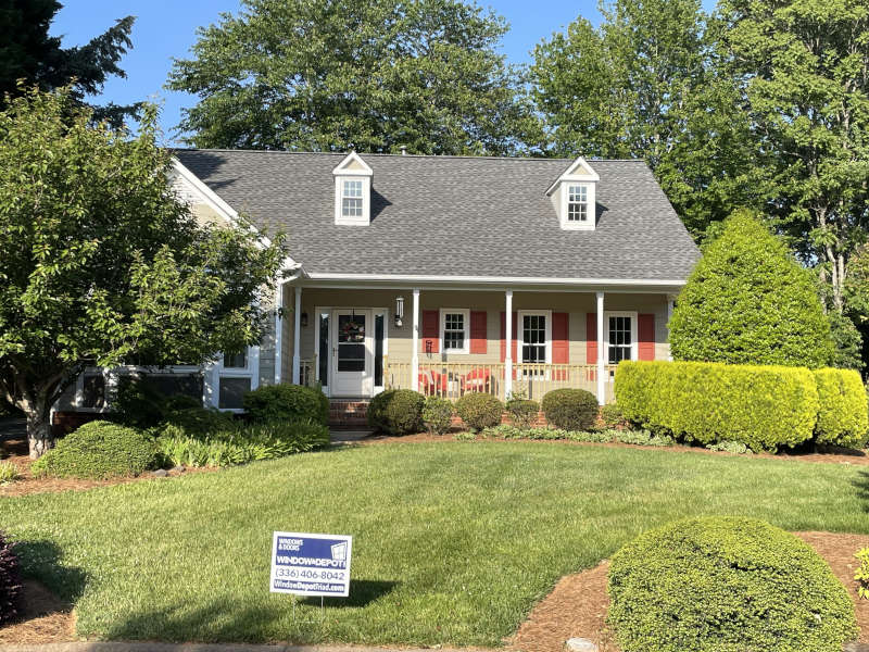 A tidy suburban house with inviting curb appeal showcases a window and gutter cleaning service sign.