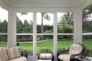Sunlight pours into a cozy sunroom, offering peaceful views of a lush, leafy backyard.