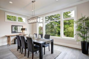 A sleek dining room exudes calm, natural light and lush views through expansive windows and doors.