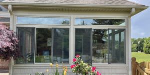 Warm light fills a sunroom with sliding windows, offering peaceful views of vibrant flowers and greenery.