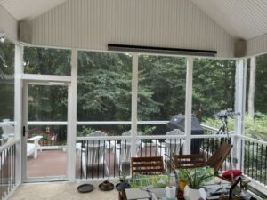 A cozy, sunlit porch opens to a serene deck, blending comfort with inviting natural views.
